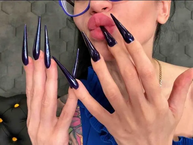 Dunkelblaue lange Nägel, scharfe Stilettos, lange Finger und Beinhaut kratzen